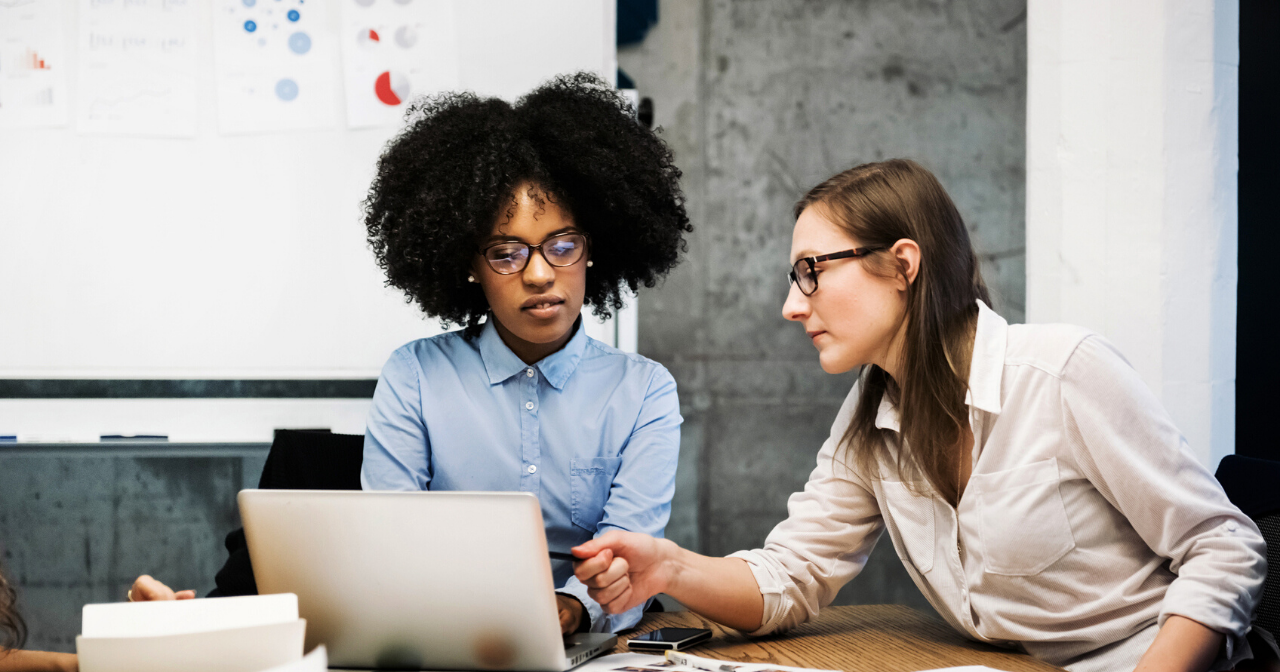Two women work at a computer together