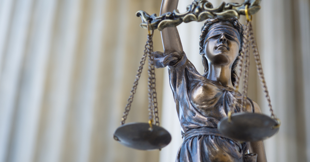 A photo of the statue of blind justice holding scales against the background of the Supreme Court's columns. 
