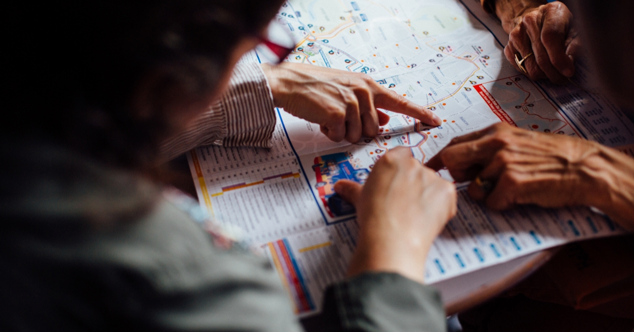 Two people bend over a map and point out specific points. 