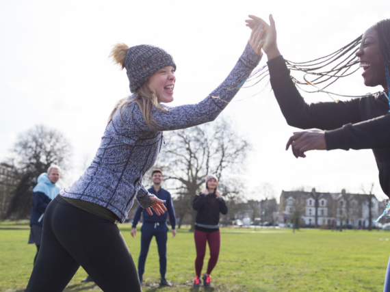 Two women high five in a field