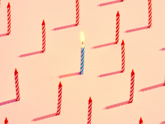 A sea of red, unlit birthday candles and one blue, lit candle in the middle. 