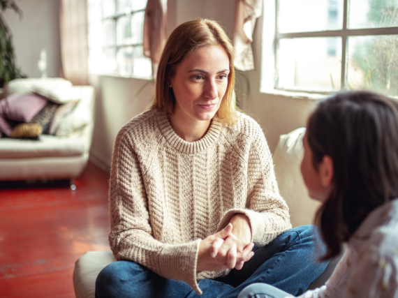 A mother and her daughter sit on the sofa and chat. 