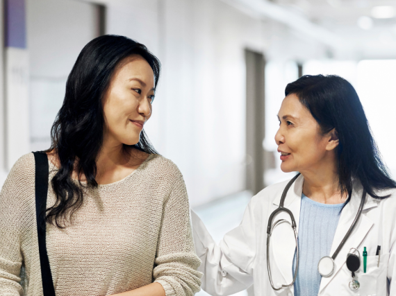 A provider and patient talk while walking down a hallway. 