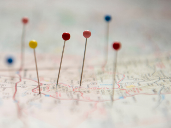A paper map with pins of different colors stuck in different places. 