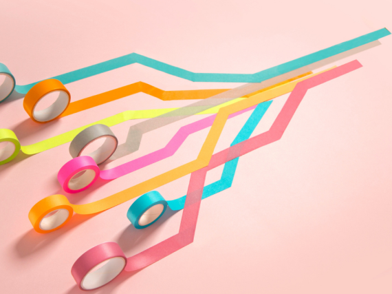 Eight different colors of tape are all rolled out and over one another. 