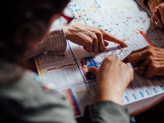 Two people bend over a map and point out specific points. 
