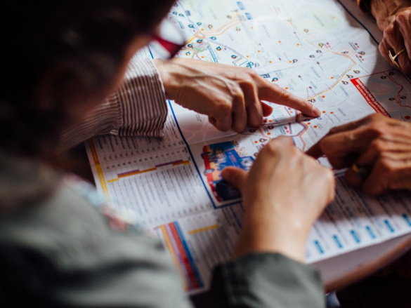 Two people bend over a map and point out specific points. 